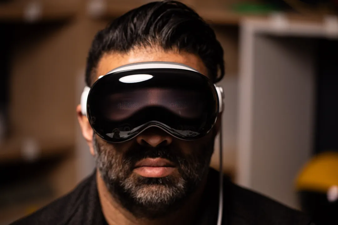 尼莱·帕特尔 (Nilay Patel) 佩戴 Vision Pro，正面显示屏上显示出他眼睛的微弱图像