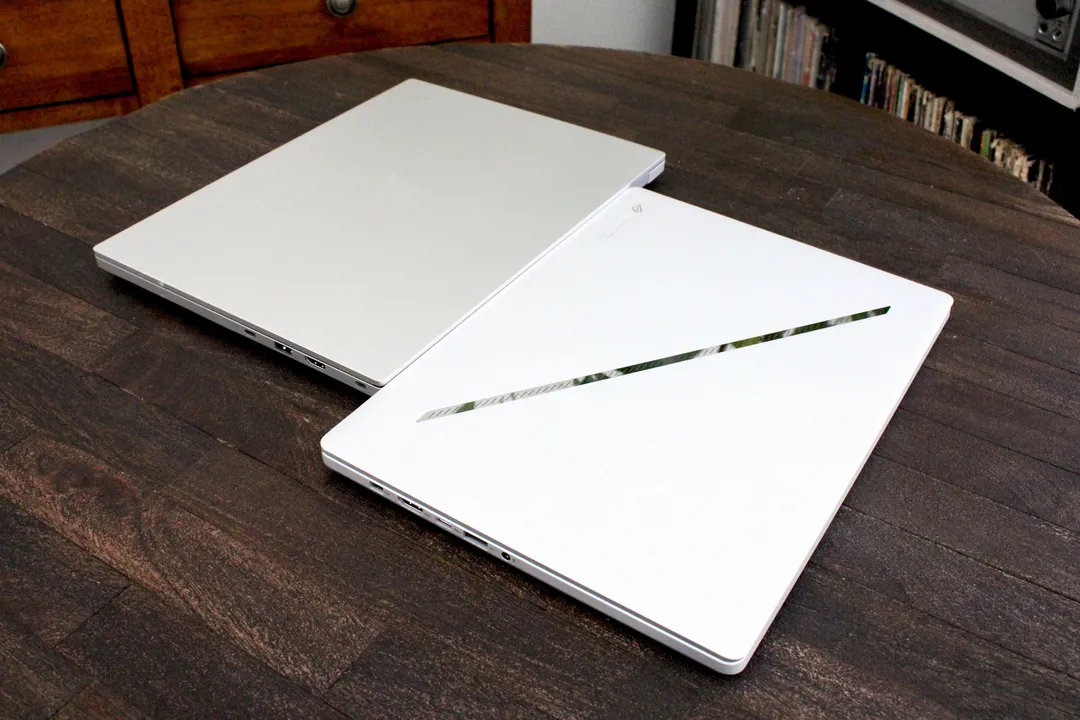 两台笔记本电脑的盖子紧挨着放在一张深色木桌上