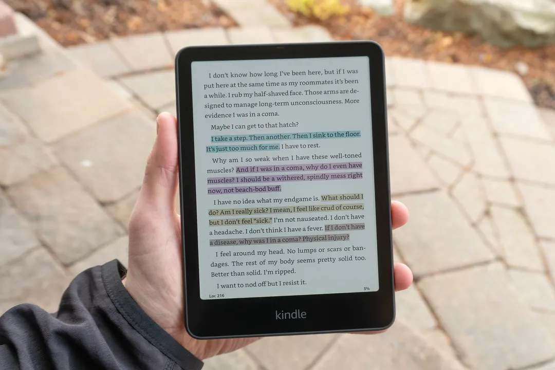 一只手拿着亚马逊 Kindle Colorsoft，屏幕上显示突出显示的文本