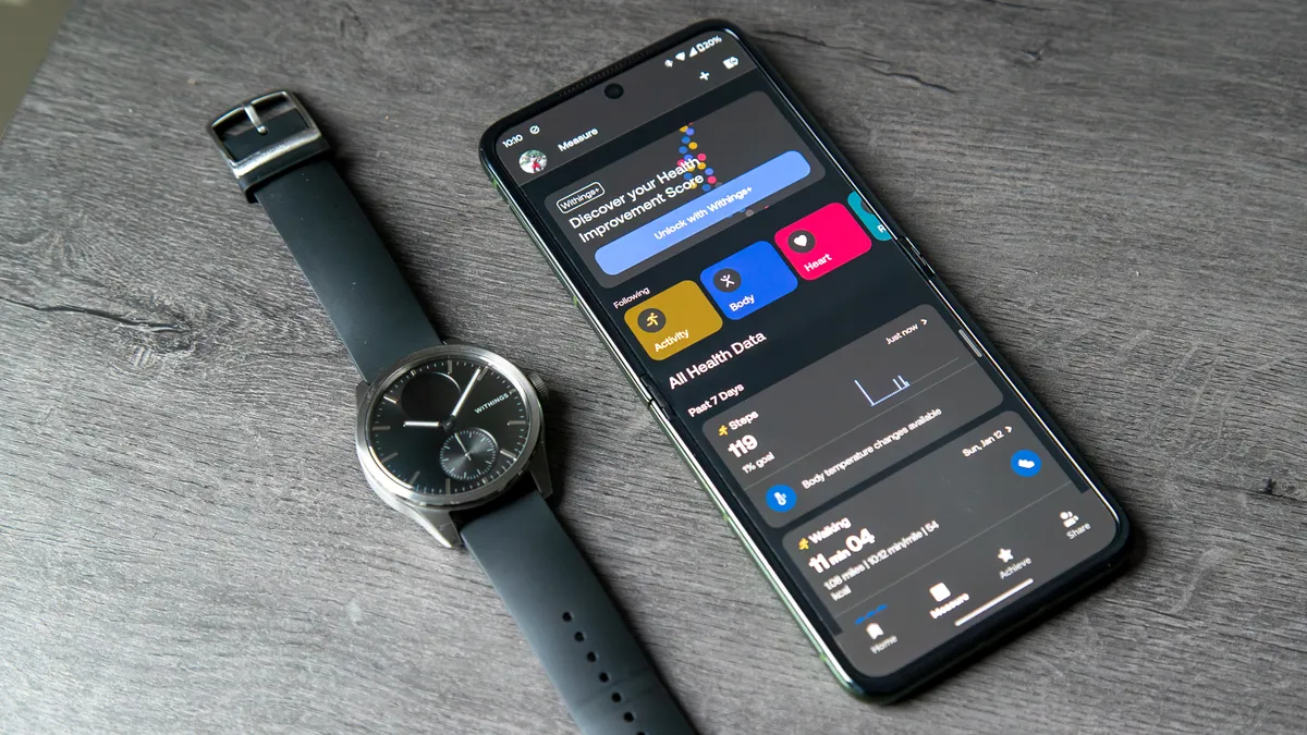 Withings ScanWatch 2 旁边是打开了 Withings 应用程序的手机
