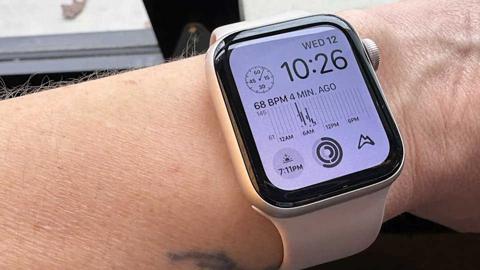 Apple Watch SE，第二代，将于 2025 年问世，佩戴在人的手臂上，靠近展示模块化表盘的窗口。