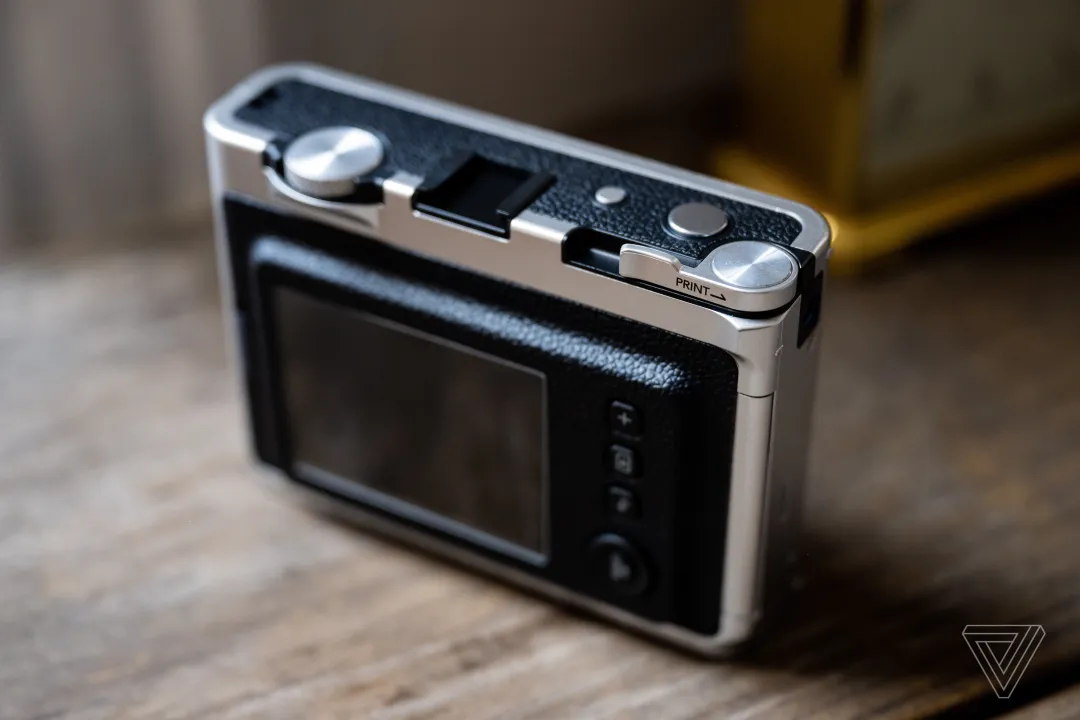 Instax Mini Evo 侧放在桌子上，大液晶屏和背面大部分可见。