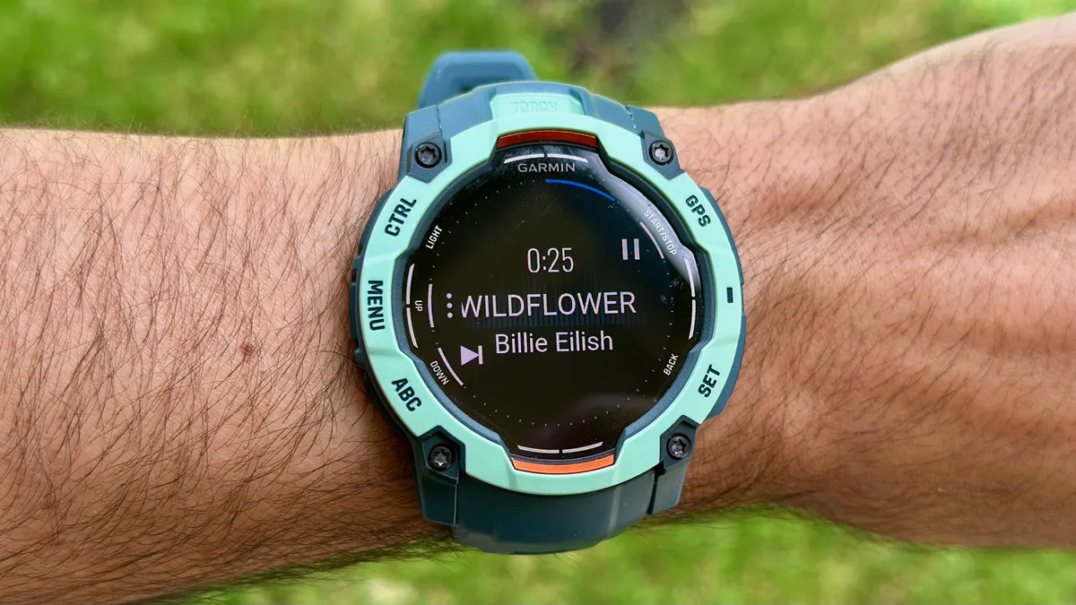 Garmin Instinct 3 50mm AMOLED 显示音乐播放控制，其中 Billie Eilish 的“Wildflower”在 0:25 处播放。
