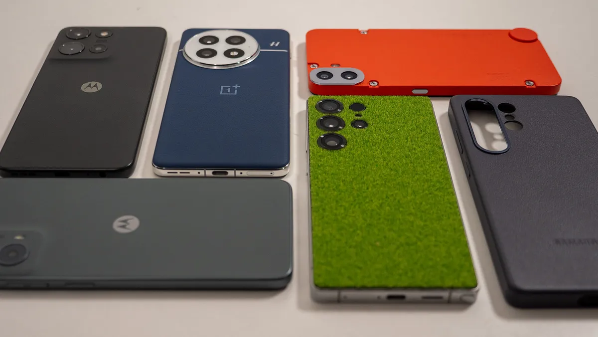 贴有 DBrand Touch Grass 保护膜的三星 Galaxy S25 Ultra，旁边是 CMF Phone 1、Moto G 5G 2024、Moto G 2025、OnePlus 13 和官方 Galaxy S25 Ultra 皮套