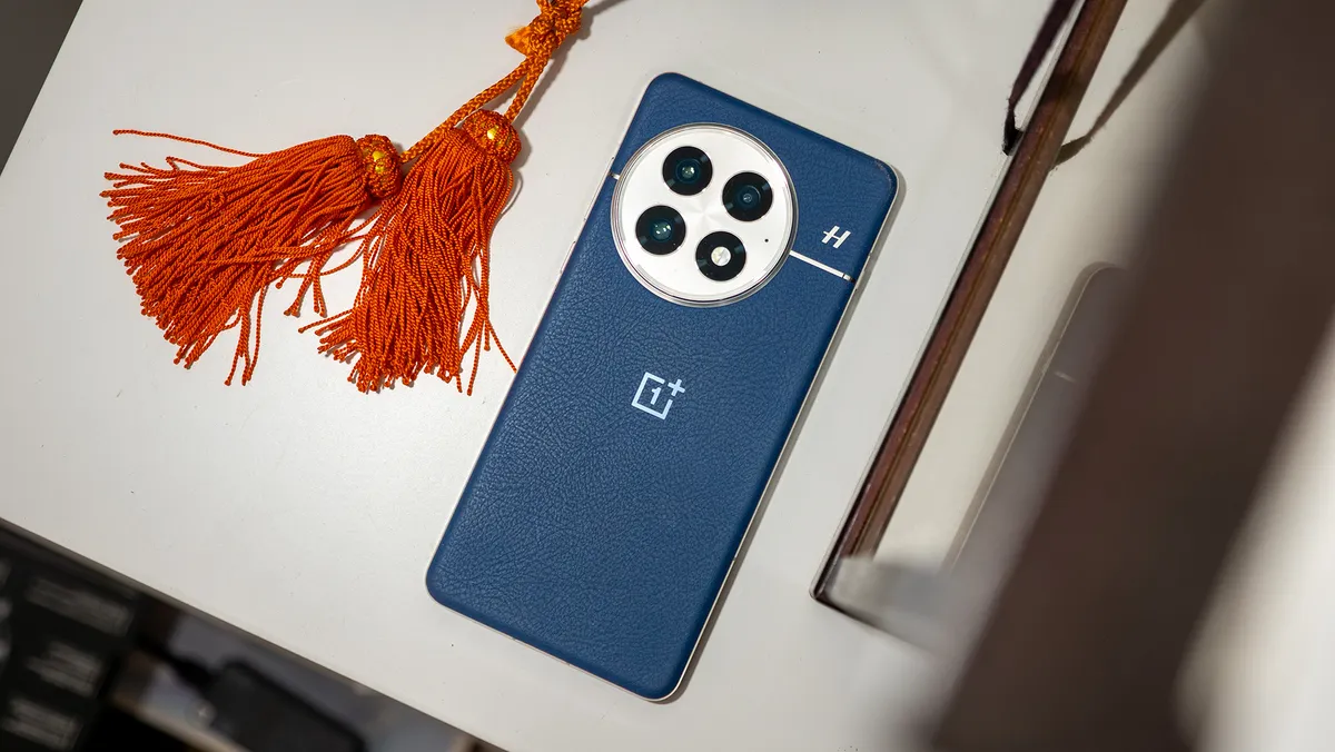 蓝色 OnePlus 13 的背面，旁边是一些橙色流苏