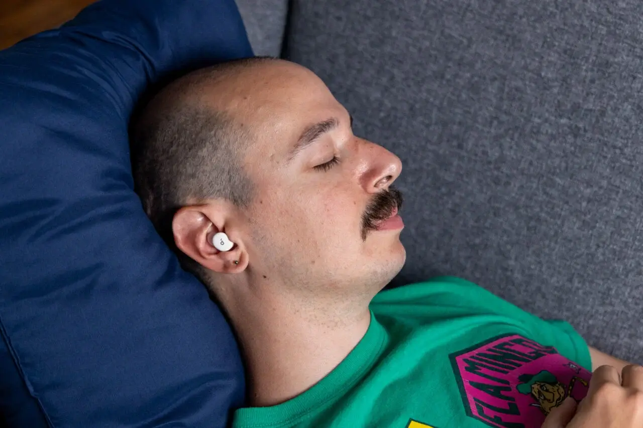 一个男人戴着 Soundcore Sleep A30 躺在沙发上休息