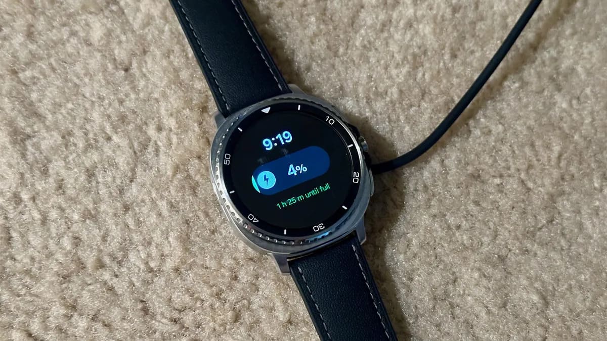 三星 Galaxy Watch 8 Classic 放在地毯上的充电器上，显示屏显示电池电量为 4%，充满还需要 1 小时 26 分钟。