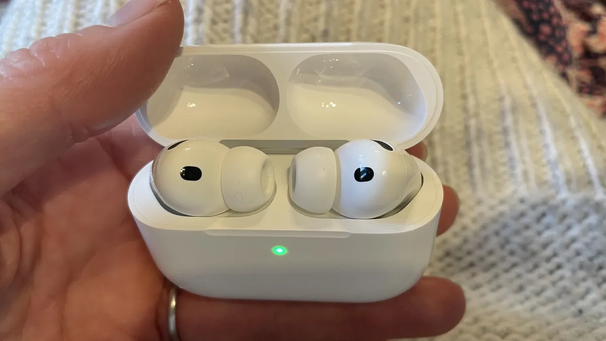 手中拿着 Apple AirPods Pro 3，背景为米色羊毛布