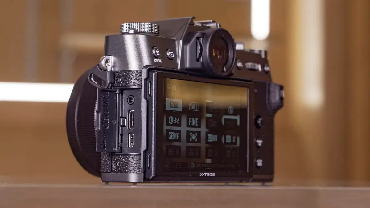 玻璃桌上的富士 X-T30 III 相机侧面，端口门打开