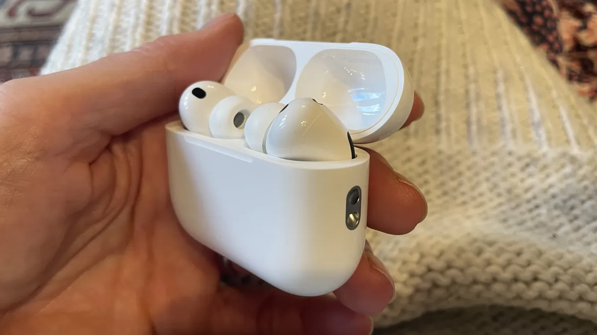 羊毛背景上，一只手拿着 AirPods Pro 3