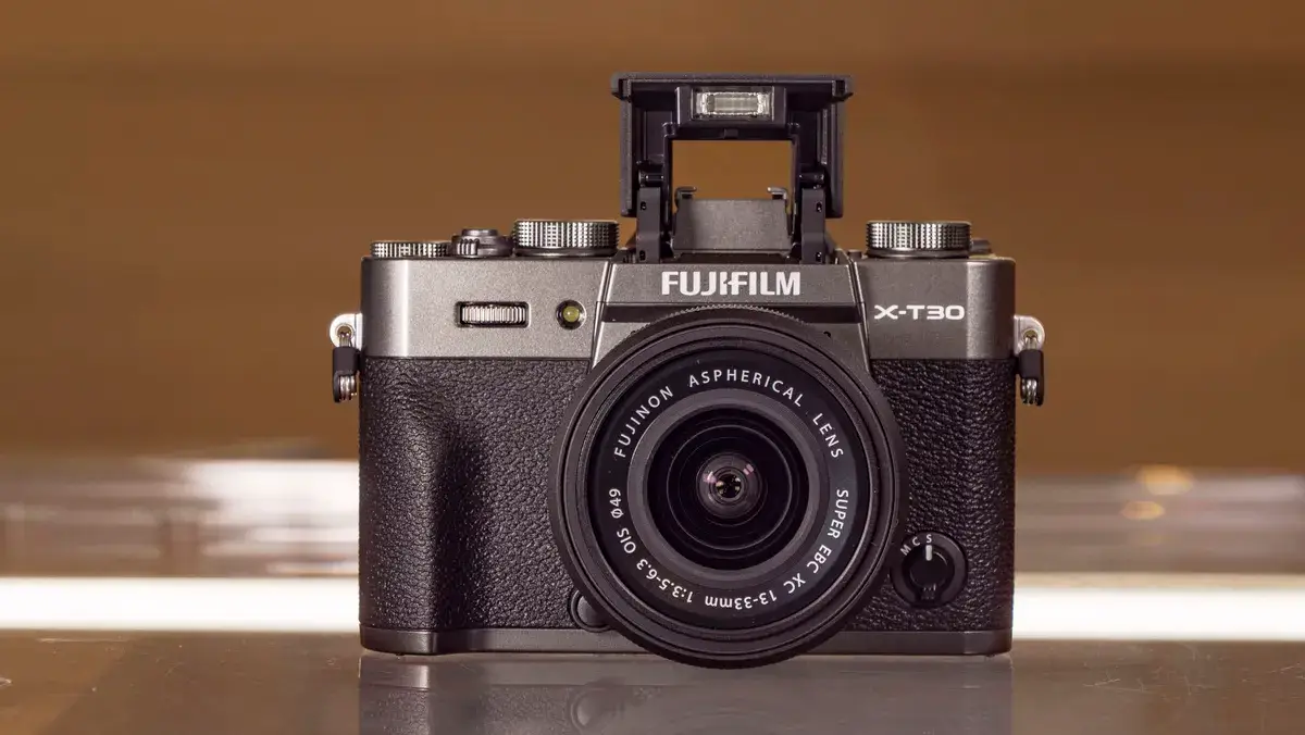 玻璃桌上放着带有弹出式闪光灯的富士 X-T30 III 相机