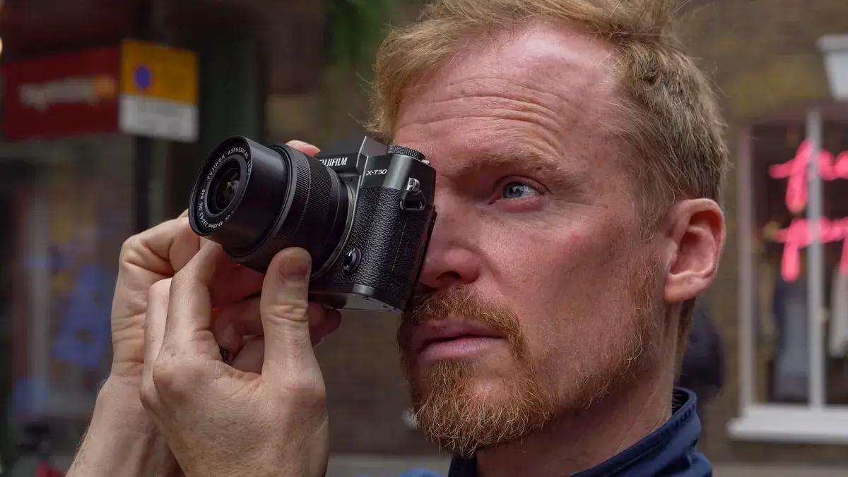 伦敦街头，一名男子将富士 X-T30 III 相机举到眼前
