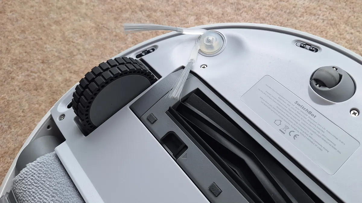 SwitchBot S20 扫地机器人翻转过来，露出底部的轮子、边刷和滚刷。