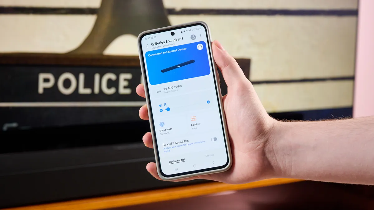 一个人拿着装有 SmartThings 应用的手机，旁边是三星 HW-Q800F 电视。