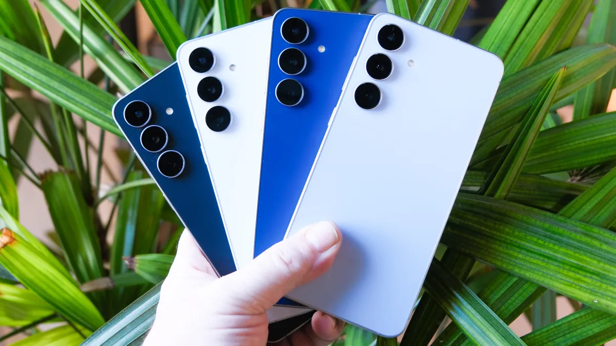 手中拿着三星 Galaxy S25 FE,身后是长长的绿叶 手中拿着三星 Galaxy S25 FE,身后是长长的绿叶